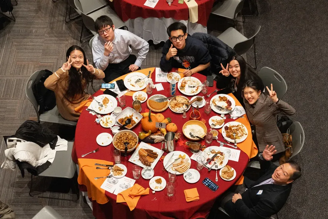 学生们坐在一张桌子上吃晚饭.