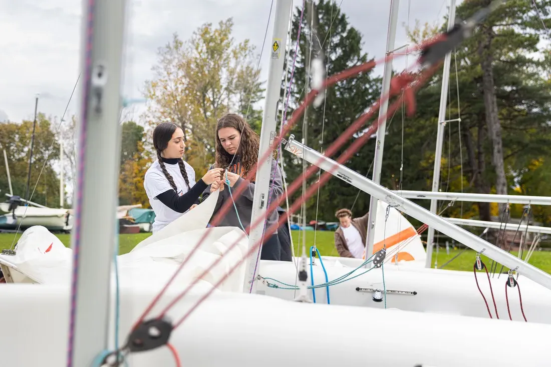 Two sailing team members maintaining their boat.