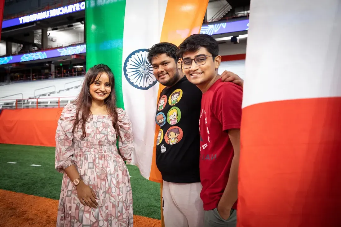 三名留学生站在各国国旗前微笑.